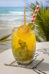 Cocktail with orange and mint in highball glass on tre beach background Copy space