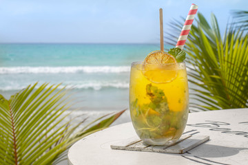 Cocktail with orange and mint in highball glass on tre beach background Copy space