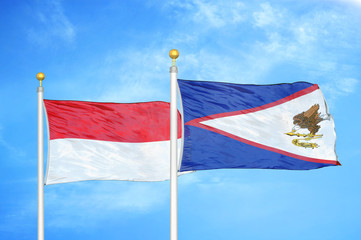 Indonesia and American Samoa two flags on flagpoles and blue cloudy sky