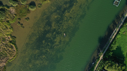 Aerial top down view of Thu Bon river with small round islets covered by green jungle grass on water. Long Tail boat is floating on river. Beautiful landscape from drone.