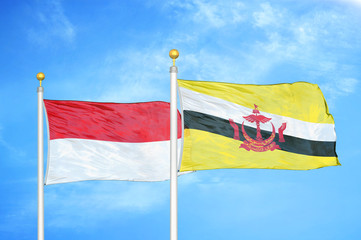 Indonesia and Brunei two flags on flagpoles and blue cloudy sky