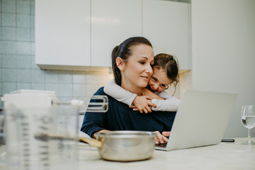 Mutter mit Tochter beim Home Office in der Küche