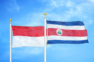 Indonesia and Costa Rica two flags on flagpoles and blue cloudy sky