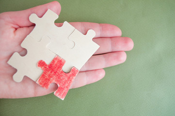 Hand holds puzzles. Red puzzle as a symbol of a nascent person. Pandemic. Epidemic. Leadership strategy. Strategy stand out.