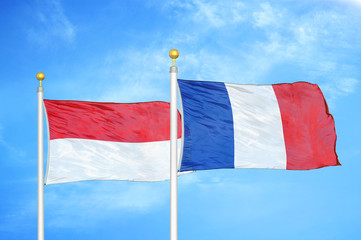 Indonesia and France two flags on flagpoles and blue cloudy sky