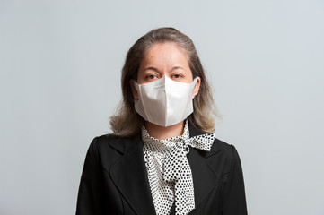 Front view of middle aged mixed race woman in formal wear wearing white disposable 3D face mask for protection against Coronavirus (COVID-19). Isolated on white background. Horizontal shot.