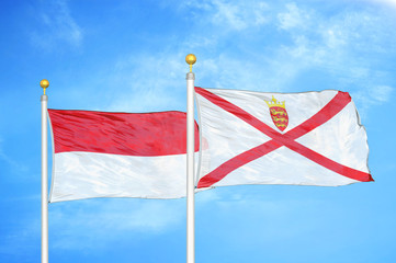 Indonesia and Jersey two flags on flagpoles and blue cloudy sky
