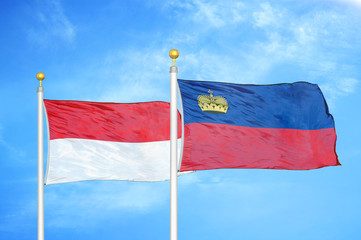 Indonesia and Liechtenstein two flags on flagpoles and blue cloudy sky