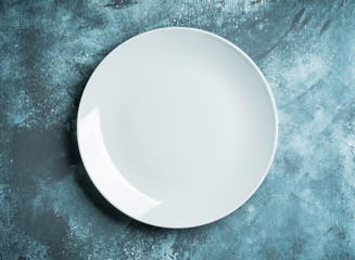 Clean white plate on the rustic background. Selective focus. Shot from above.