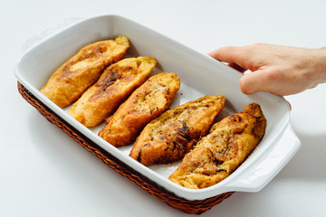 Male hand holding a tray with torrijas, a typical Spanish sweet fried toasts of sliced bread soaked in eggs and milk, on white background