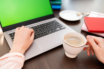 Woman hands typing laptop computer with blank screen for mock up template background, business technology and lifestyle background concept. She is drinking coffee.