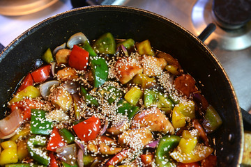 Freshly prepared stir fry with chicken and vegetables including onions, red, yellow and green capsicum in a wok