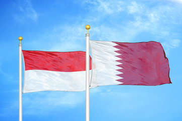 Indonesia and Qatar two flags on flagpoles and blue cloudy sky