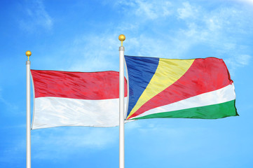 Indonesia and Seychelles two flags on flagpoles and blue cloudy sky