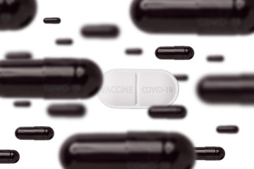 Many black pills with Covid-19 and one white pill with vaccine on white background. Coronavirus against vaccine. Antivirus struggle.