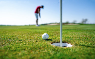 Golfer putting golf ball on the green golf. One of golf players going to hit it right into the hole...