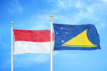 Indonesia and Tokelau two flags on flagpoles and blue cloudy sky