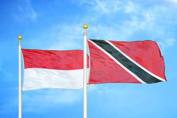 Indonesia and Trinidad and Tobago two flags on flagpoles and blue cloudy sky
