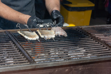 Chef make on grill and serve delicious white sea fish fillet at the street market
