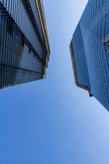 Skyscraper glass facades at a bright sunny day on the blue sky background. Economy finances and business activity concept. Low angle view