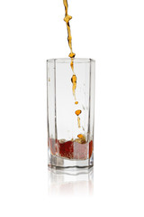 Beer glass with a stream of dark beer pouring into it on a white background with a reflection