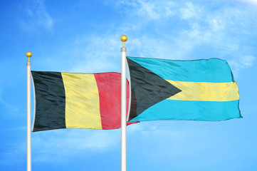 Belgium and Bahamas two flags on flagpoles and blue cloudy sky