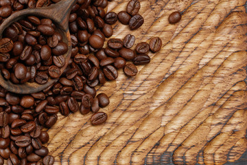 Wooden spoon with full coffee beans on a wooden table. Selective focus