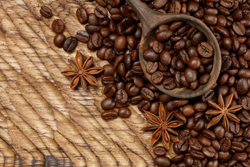 Wooden spoon with full coffee beans and star anise on a wooden table. Selective focus