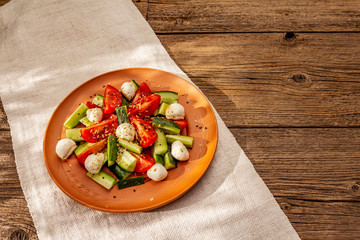 Fresh salad from tomato, cucumber and baby mozzarella. Sunny lunch with crusty bread
