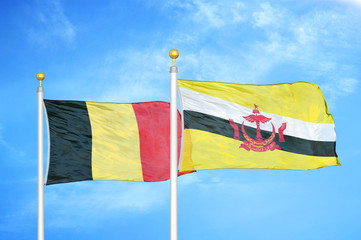 Belgium and Brunei two flags on flagpoles and blue cloudy sky