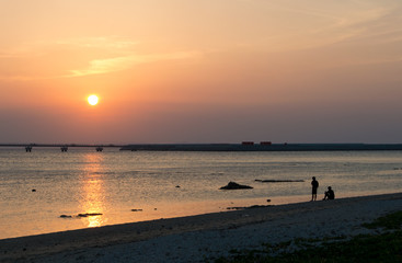 オレンジ色の夕日と飛行場の誘導灯とシルエットの二人