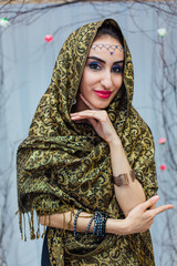 Beautiful eastern woman with makeup and jewelry wearing headscarf.