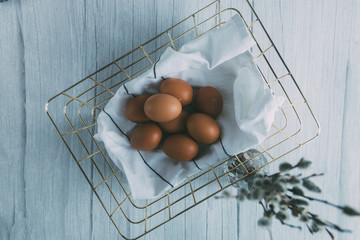 Raw eggs in basket on wooden table