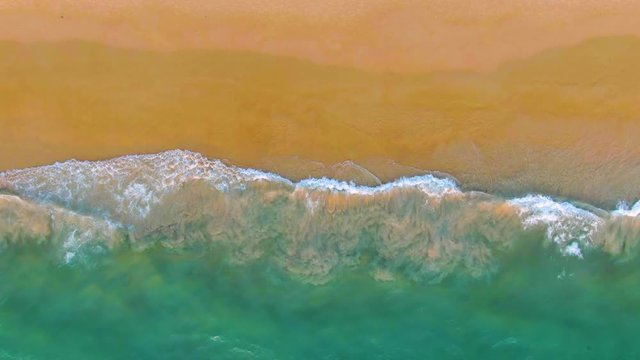 Top view of a tropical sandy resort beach. Ocean waves. Aerial 4k view