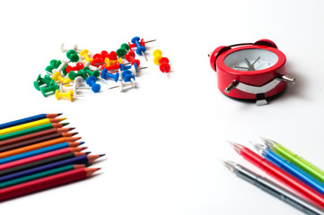 Pencils, watches, push pins and colored pens on a white background. Distance learning concept