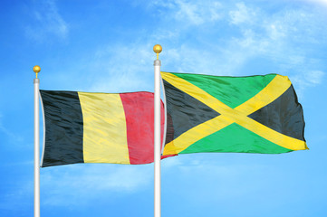 Belgium and Jamaica two flags on flagpoles and blue cloudy sky
