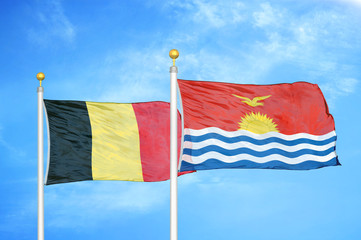 Belgium and Kiribati two flags on flagpoles and blue cloudy sky