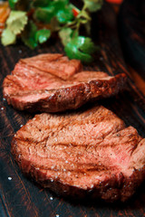 Thick juicy portions of fried fillet steak served on an old wooden board.