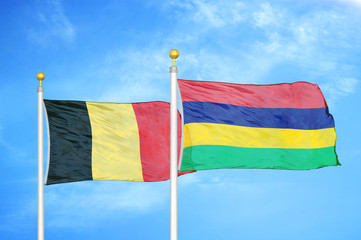 Belgium and Mauritius two flags on flagpoles and blue cloudy sky