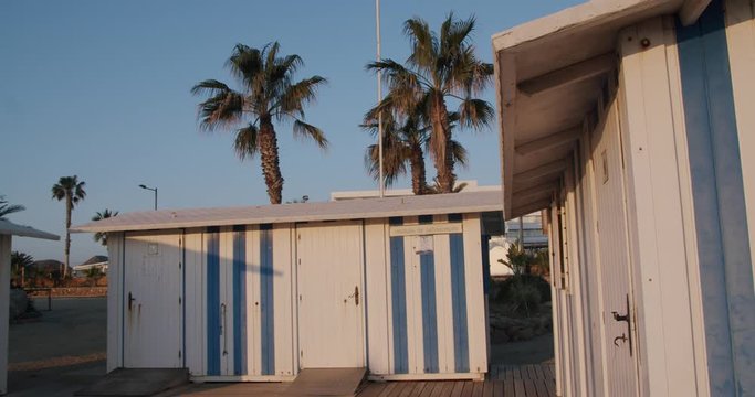 Landscape sunrise shot of blue and white bathing boxes, palm trees in Almeria, Spain