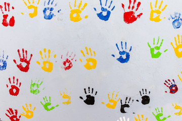 Multicolored handprints on a light gray wall. Background.