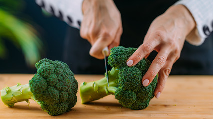 Cutting fresh organic broccoli, superfood rich in vitamin K, vitamin C, folic acid, potassium, phytonutrients and fibers