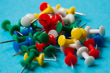Multicolored push pins on a blue background macro closeup