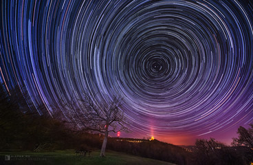 Night sky star trail over the old tree and mountains