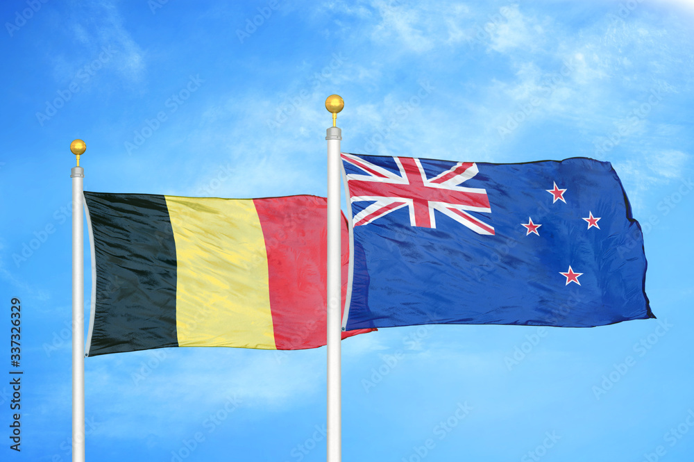 Wall mural belgium and new zealand two flags on flagpoles and blue cloudy sky