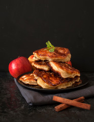 Pancakes with apples and honey on a dark background.