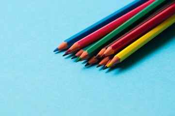 Set of colored pencils on blue paper for design.