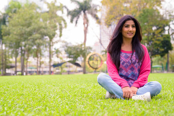 Happy young beautiful Persian woman relaxing at the park