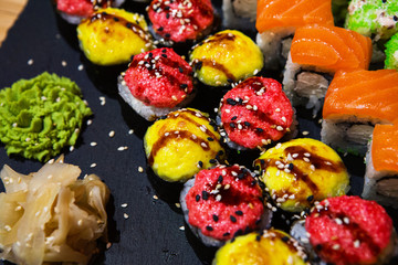 Set of rolls on a black plate with wasabi and ginger