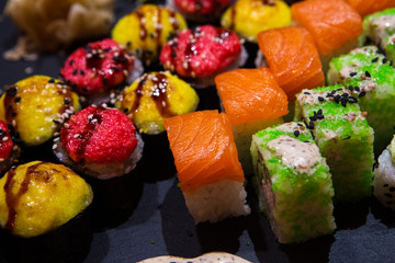 Set of rolls on a black plate with wasabi and ginger